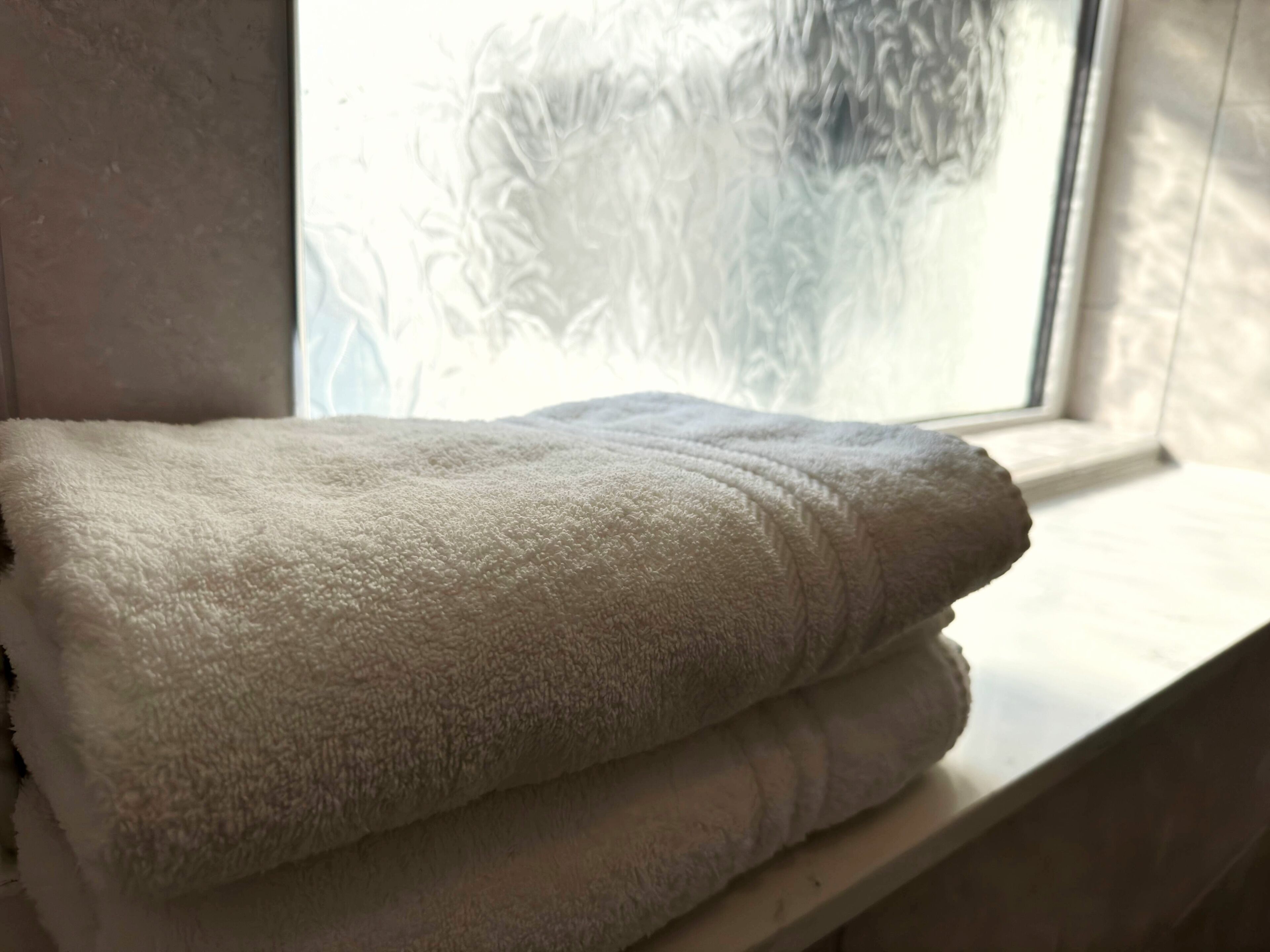 A white towel folded neatly on a window sill.