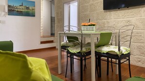 Un'area pranzo con tavolo e sedie, una televisione a schermo piatto montata a parete e un quadro che raffigura una veduta cittadina.