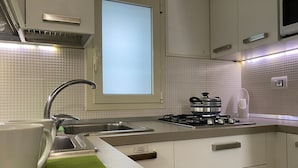 Una cucina moderna con lavello in acciaio inossidabile, un piano cottura e una finestra sopra il lavello.