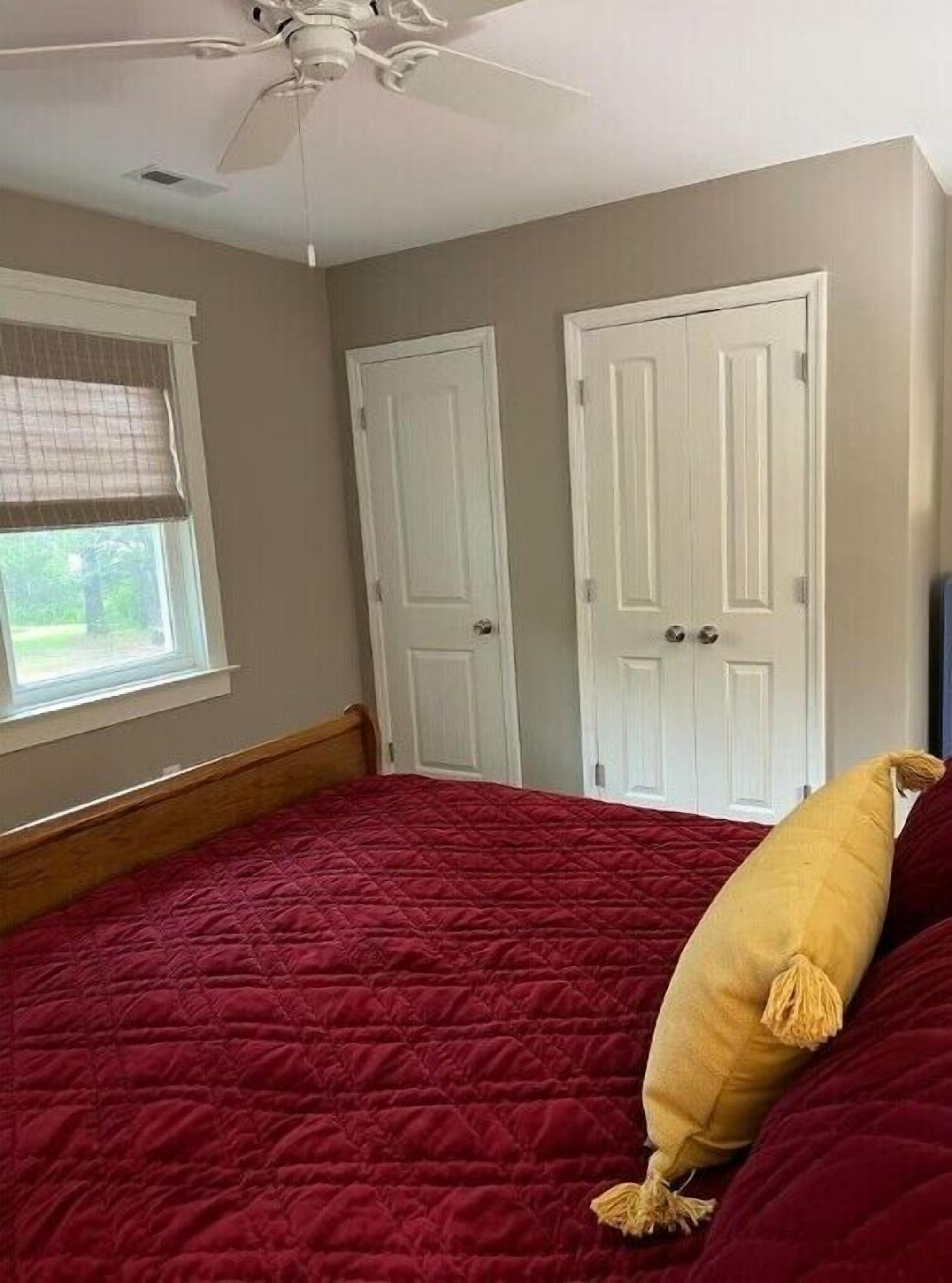 A bedroom with a bed, a ceiling fan, and two white doors.