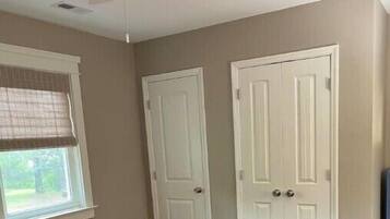 A bedroom with a bed, a ceiling fan, and two white doors.