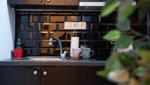 A kitchen with dark cabinets, a stainless steel sink, and two electrical outlets on the wall. - Beautiful studio close to the archaeological museum (Athina)