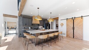 A modern kitchen with a large island, bar stools, and pendant lighting.