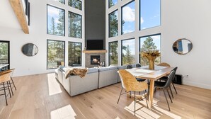 A spacious living area with a large window, a fireplace, and a dining table with chairs.