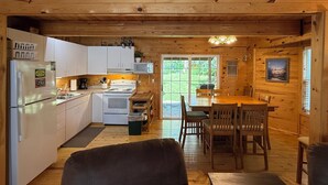Een blokhut interieur met een keuken, een eethoek en een groot raam.