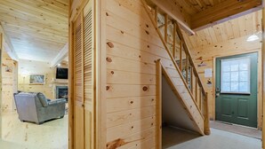 Een houten interieur met een trap, een bank en een groene deur.