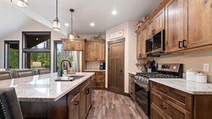 Une cuisine moderne avec des meubles en bois, un grand îlot central et un four encastré.