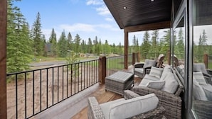 Un espace extérieur abrité, aménagé avec des meubles en osier et offrant une vue sur un paysage boisé.
