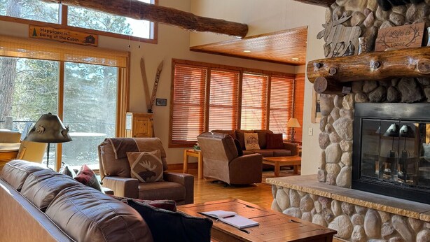 A cabin interior with a stone fireplace, wooden ceiling beams, and a large moose head decoration. - Moose Trail Lodge- Terry Peak with Hot Tub (Lead)