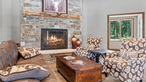 A cozy living room with a stone fireplace, leather sofa, patterned armchair, and a rustic coffee table. - Moonlit Summit with hot tub, lots of great parking and views (Lead)