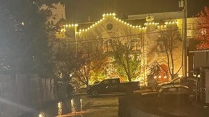 Een gebouw met een symmetrische gevel, verlicht met lichtslingers, en een auto geparkeerd ervoor.
