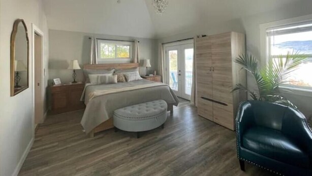Een slaapkamer met een bed, nachtkastjes, een kledingkast, een stoel en een raam.
