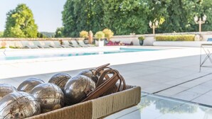 Zona de piscina con sillones de descanso y una cesta de mimbre con objetos metálicos.