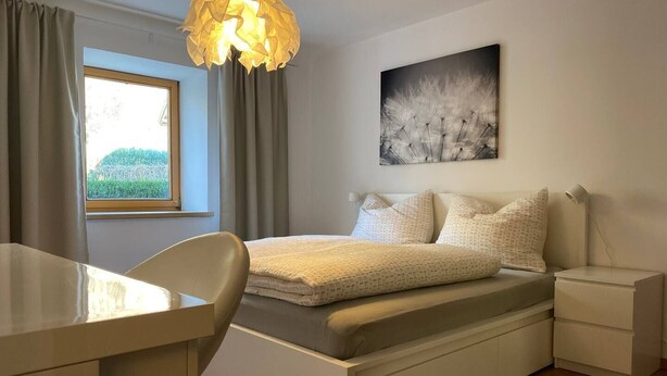 Une chambre moderne avec un lit, des tables de chevet, un bureau et une fenêtre avec des rideaux.