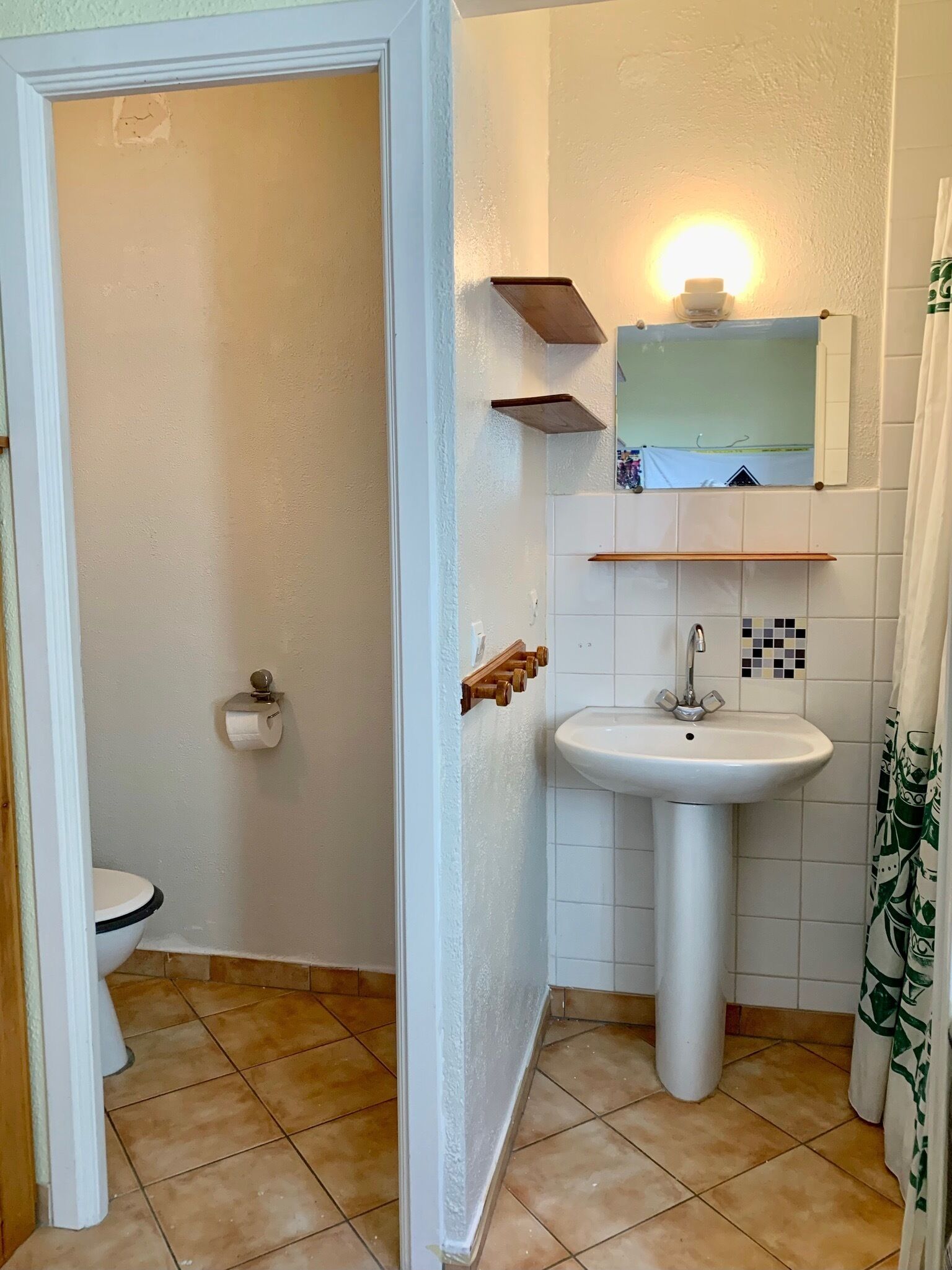 Un bagno con il water, un lavandino e uno specchio.