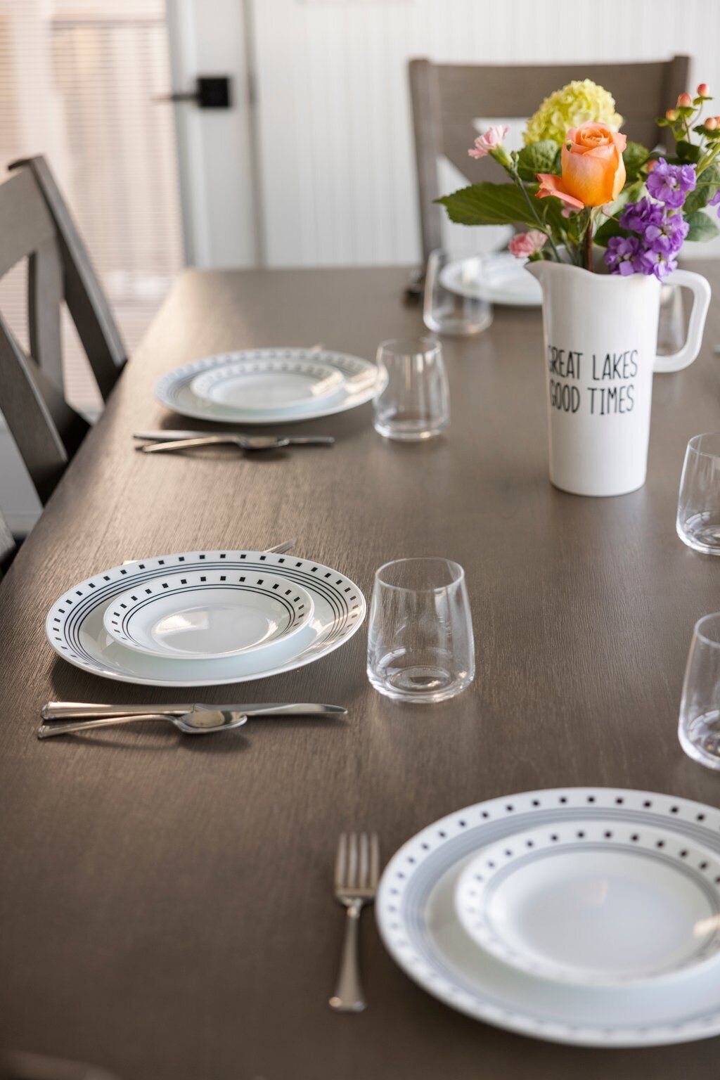 Una mesa de comedor lista con platos, cubiertos y una taza.