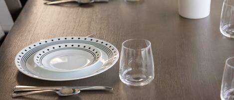 Una mesa de comedor lista con platos, cubiertos y una taza.