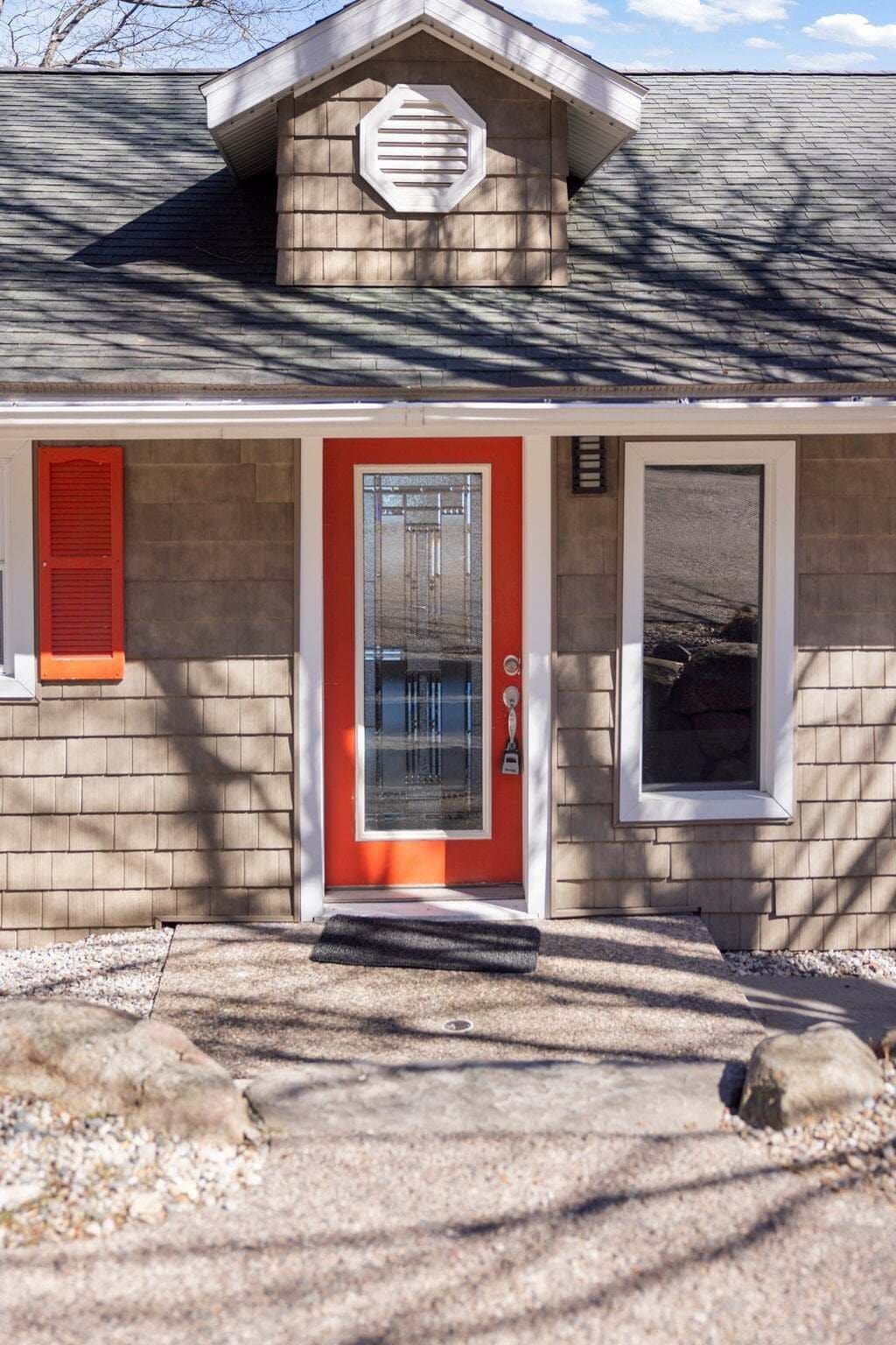 A house with a red door, a small porch, and a garage door.