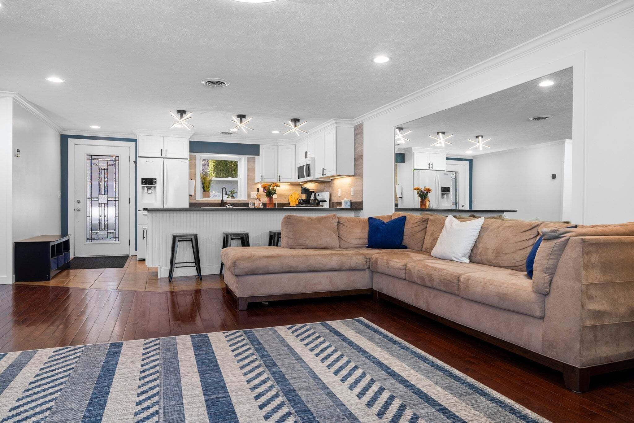 Une cuisine moderne avec des armoires blanches, un four encastré et un coin bar.