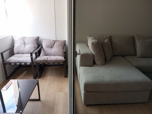 A modern living room with a sofa and a chair, both in neutral tones, and a small table.