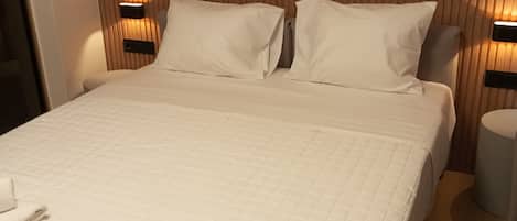 A neatly made bed with a quilted white bedspread, two pillows, and a folded towel on the bed.