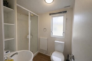 A bathroom with a shower, toilet, and a sink.