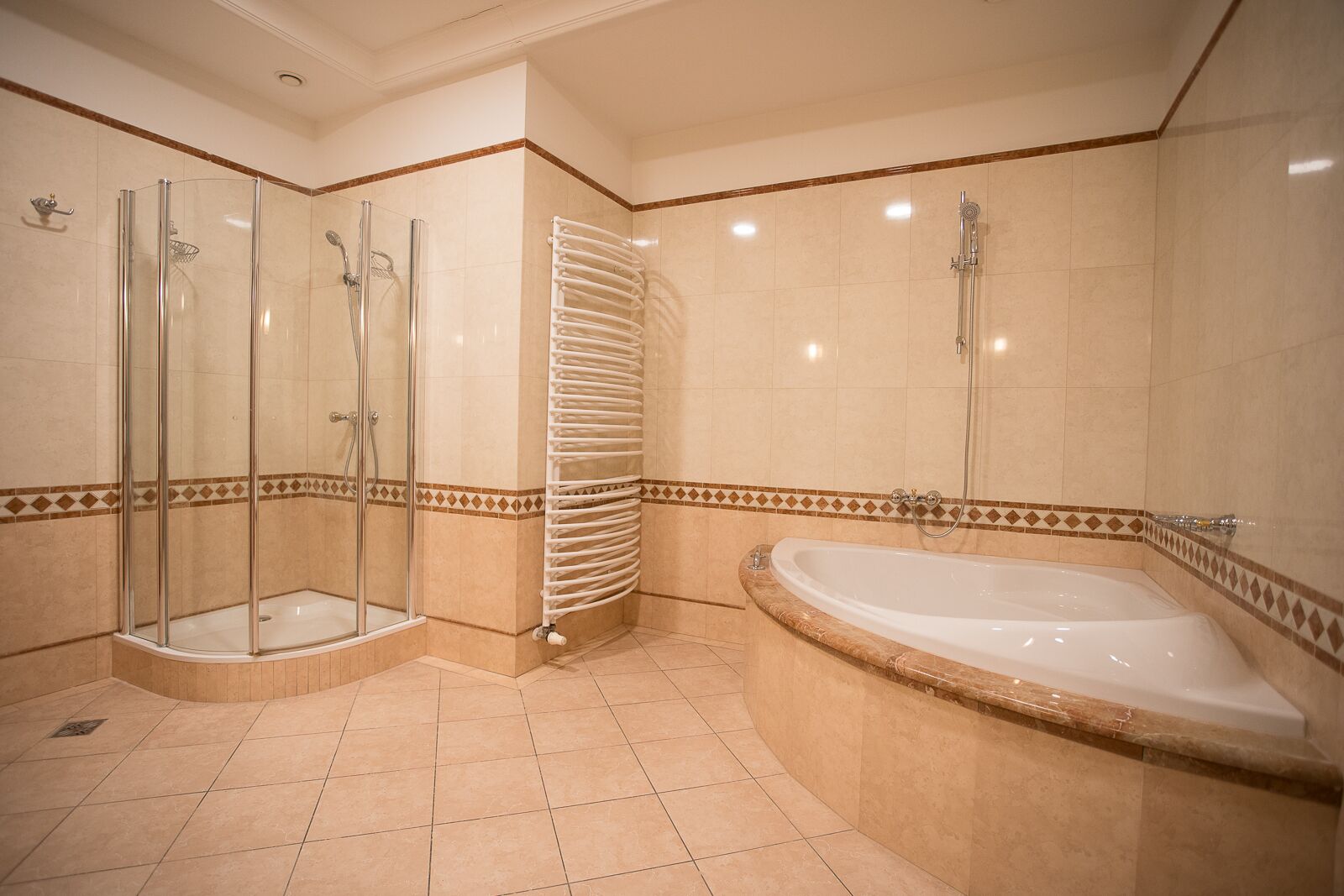 A bathroom with a glass-enclosed shower, a bathtub, and a towel rack.