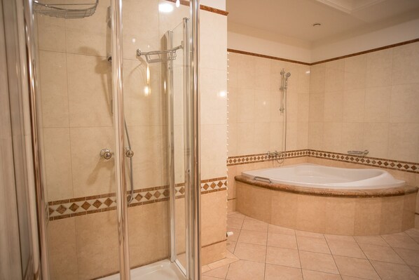 A bathroom with a glass-enclosed shower, a bathtub, and tiled walls. - Hotel Golden Palace (Goed)