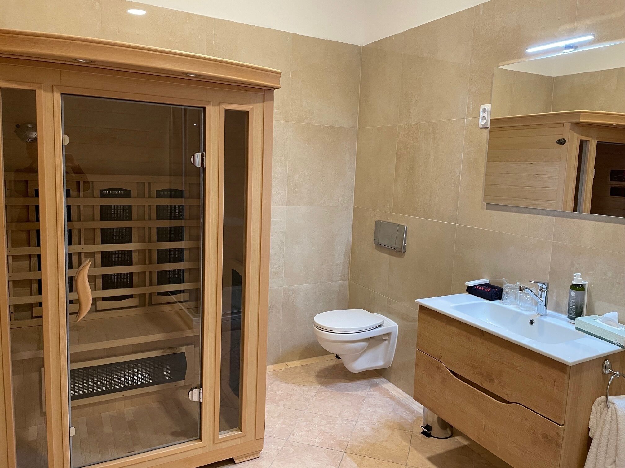 A modern bathroom with a glass-enclosed shower, a white toilet, and a vanity with a mirror and sink.