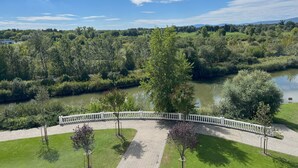 Un parque con un sendero pavimentado, árboles y un río.