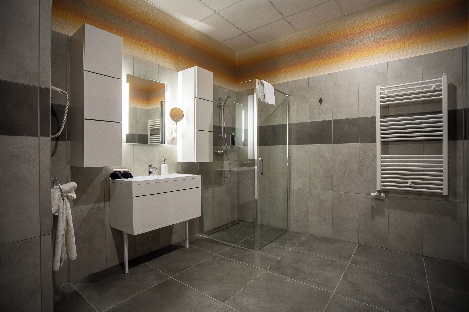 A modern bathroom with a glass shower enclosure, a white vanity, and a towel rack.