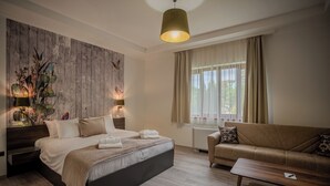 Un dormitorio moderno con una cama grande, un sofá, una mesita de centro y una lámpara de pared.