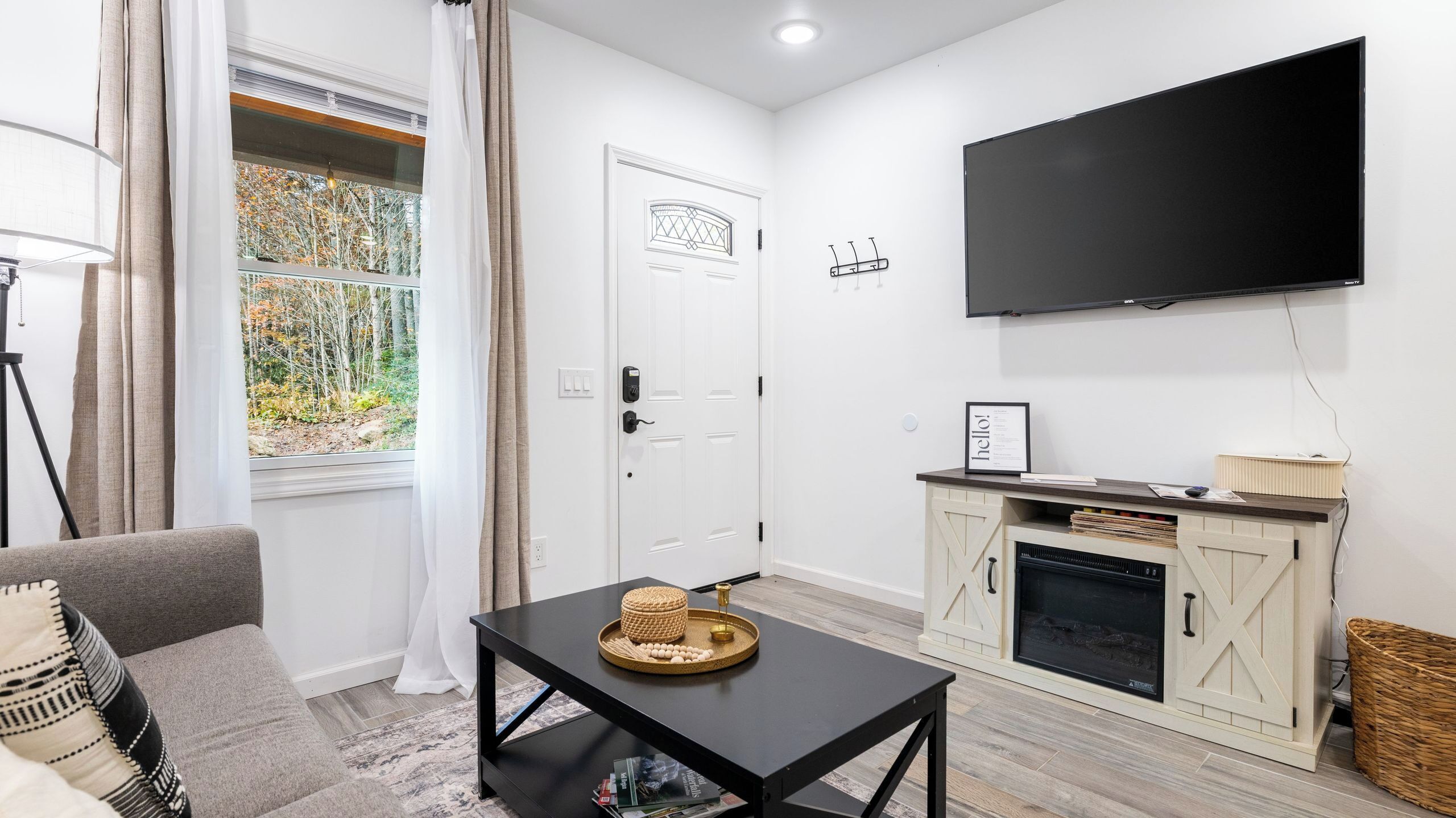 A modern living room with a flat-screen TV, a fireplace, a dining table with a basket, and a sofa.
