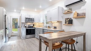 Une cuisine moderne avec des meubles blancs, des appareils en acier inoxydable et une table à manger en bois.