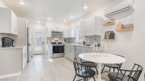 A modern kitchen with white cabinetry, a built-in oven, and a dining area with a round table and chairs. - Bears Place by Avantstay Cozy Mountain Cabin in Brevard + Firepit (Brevard)
