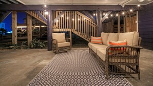 Ein Außenbereich mit Terrasse, einem gemusterten Teppich, Korbmöbeln und einer Treppe.