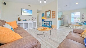 Ein Wohnzimmer mit braunen Ledersofas, einem Couchtisch und einer Küchenzeile inklusive Kühlschrank und Schränken.