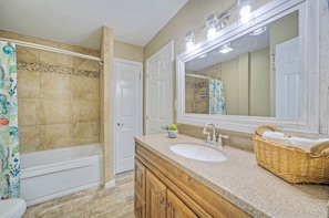 Une salle de bain avec une baignoire, un lavabo, un miroir et un rideau de douche.