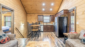 Accogliente interno di una baita con cucina, zona pranzo e due divani.