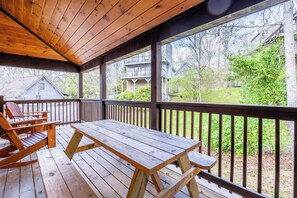 A wooden deck with a picnic table and Adirondack chairs, overlooking a residential area with houses and trees. - The Wacky Woodpecker by Avantstay Game Room, Private Hot Tub, & Pool Access! (Pigeon Forge)