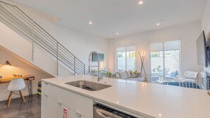 Una cocina moderna con lavavajillas integrado, un comedor con mesa y sillas, y una escalera.