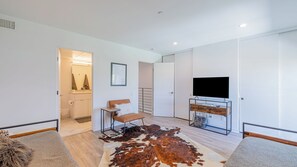 A modern living room with a large flat-screen TV, a brown leather sofa, a glass coffee table, a cowhide rug, and a minimalist design. - Zanjero by Avantstay Mins From Downtown Palm Springs Private Terrace, Shared Pool (Palm Springs)
