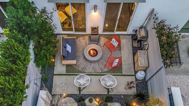 An outdoor patio with a fire pit, seating, and a view of the interior. - Zanjero by Avantstay Mins From Downtown Palm Springs Private Terrace, Shared Pool (Palm Springs)
