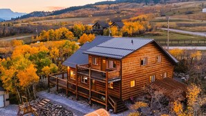 A wooden cabin with a balcony, surrounded by autumn foliage. - Modern Timber- Hot tub, sauna, theatre, climb wall (Beaver Mines)