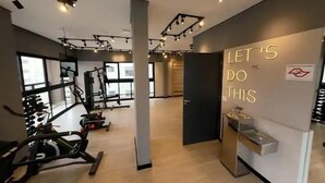 Ein Fitnessstudio mit Trainingsgeräten, einem motivierenden Wandspruch und großen Fenstern für natürliches Licht.