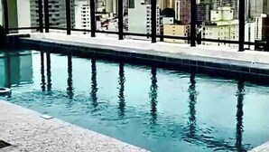 Ein Pool auf dem Dach mit Blick auf die Stadt, umgeben von einem Metallgeländer.