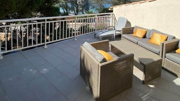 A terrace with wicker furniture and a view of the sea.