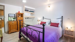 A bedroom with a bed, wooden wardrobe, shelves, and a nightstand. - LA Girage DE BEL AIR (Amboise)