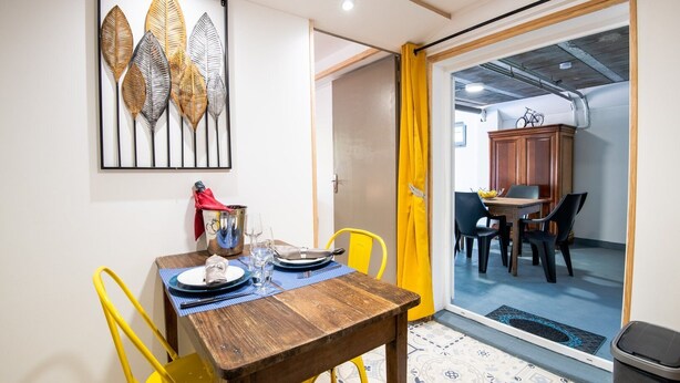 A dining area with a wooden table, yellow chairs, and a dining set. - LA Girage DE BEL AIR (Amboise)