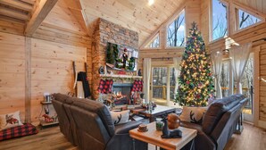 Ein gemütliches Blockhaus-Interieur mit Kamin, Ledersofas und einem geschmückten Weihnachtsbaum.